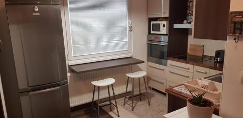 a kitchen with a refrigerator and two stools in it at Apartman Zvolen in Zvolen