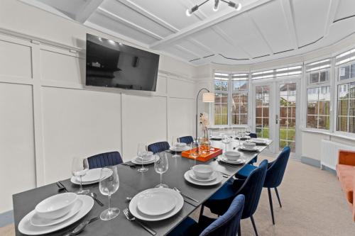 a dining room with a long table and chairs at 5 Bedroom House 13 Beds Across From Tube Station in London