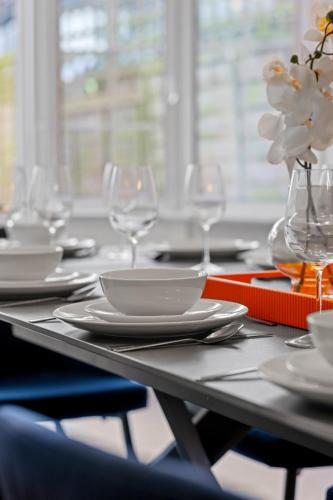 a table with plates and glasses and a vase with flowers at 5 Bedroom House 13 Beds Across From Tube Station in London