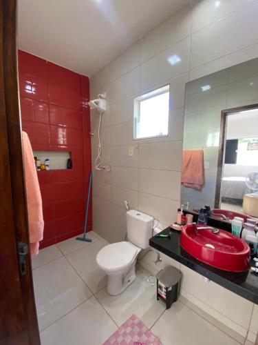 a bathroom with a white toilet and a red sink at Suíte na praia do amor in Conde