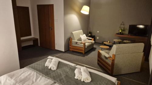 a room with a bed and a chair and a living room at Penzion Jelínek in Opočno