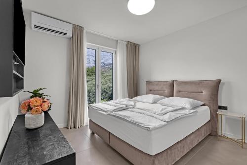 a white bedroom with a large bed and a window at Apartment Adriatic Pearl -Makarska Exklusiv in Tučepi
