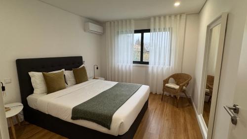 a bedroom with a bed and a window and a chair at Ri&Vale Alojamentos in Vieira do Minho