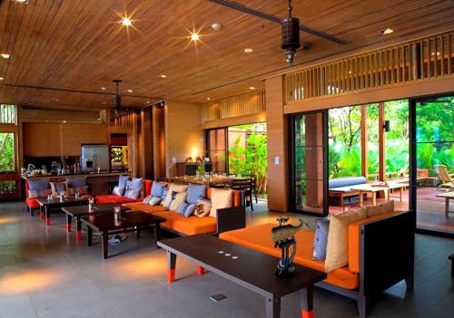 a living room with couches and tables and windows at Sri Panwa Phuket Luxury Pool Villa Hotel - SHA Plus in Panwa Beach
