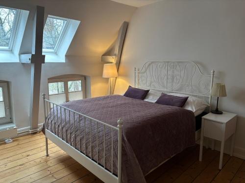 a bedroom with a bed with a purple comforter and two windows at Villa Friedenstraße 11 in Lüneburg