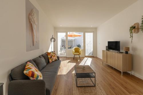 a living room with a gray couch and a table at The Bliss House in Lourinhã