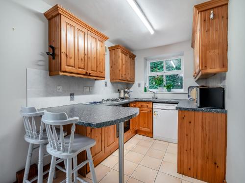 a kitchen with wooden cabinets and a counter with stools at Little Barn - 16438 in York