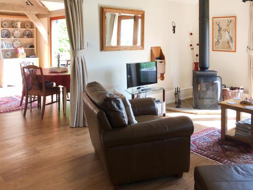 ein Wohnzimmer mit Ledersofa und Kamin in der Unterkunft Swallows Barn in Dallington