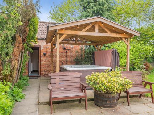 a wooden pavilion with two benches and a hot tub at The Granary - 16437 in York