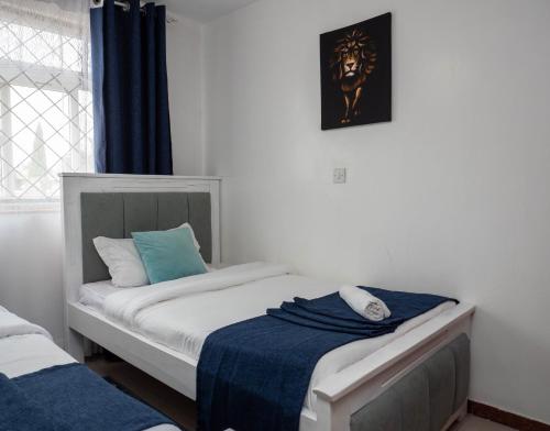 a bedroom with a bed with a blue blanket on it at Perfect Palm Condos-N12 in Nakuru