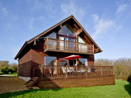 a log house with a balcony and a deck at Ash Lodge - Retallack in Saint Columb Major