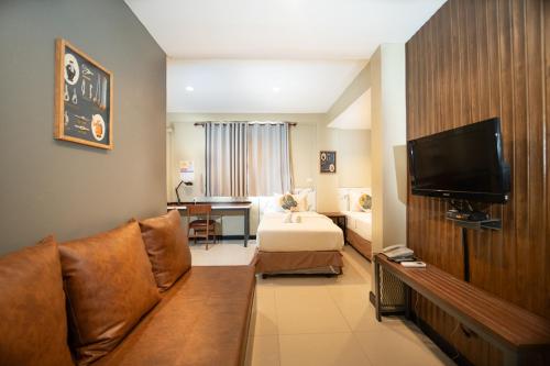 a hotel room with a bed and a television at The Palm Hotel in Salaya