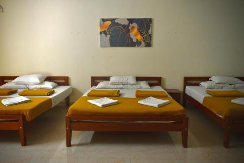 two beds in a room with yellow sheets at Gandhada Goodu Retreat in Kanakapura