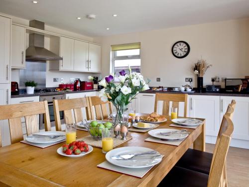 a dining room table with a vase of flowers on it at Cedar Lodge - Retallack in Saint Columb Major
