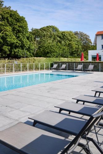 Una fila de tumbonas junto a una piscina. en ibis De Haan, en De Haan