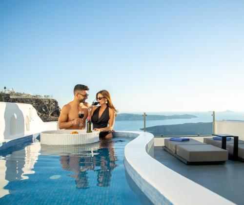 a man and a woman sitting in a swimming pool at Pegasus Suites & Spa in Imerovigli