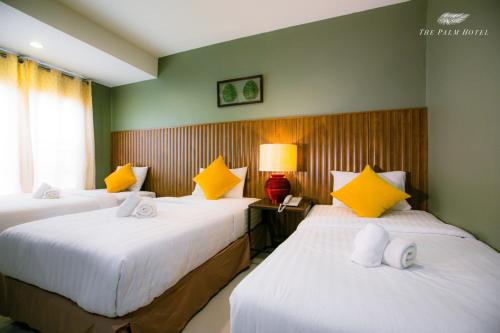 a hotel room with two beds with yellow and white pillows at The Palm Hotel in Salaya