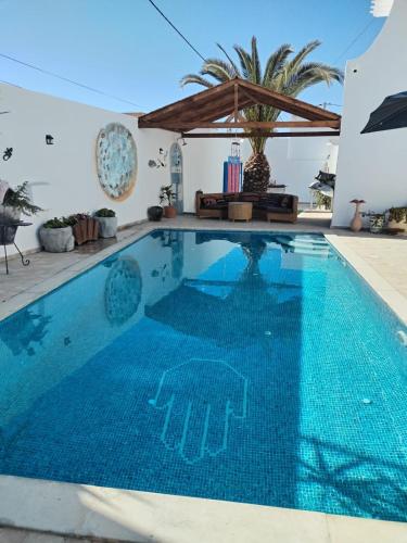a swimming pool in a villa with a blue pool at Maison Cally in Midoun