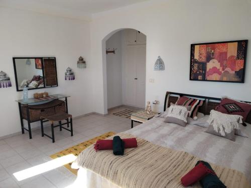 a bedroom with a large bed and a desk at Maison Cally in Midoun