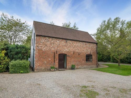 a brick building with a door and a gravel driveway at The Hayloft - 17238 in York