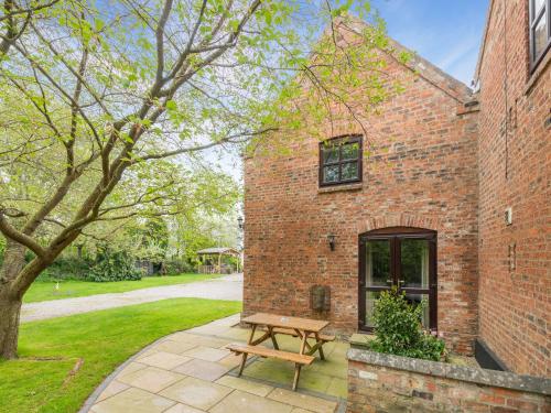 a wooden bench sitting outside of a brick building at The Hayloft - 17238 in York