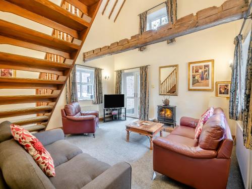 a living room with two couches and a staircase at The Hayloft - 17238 in York