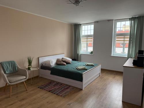 a bedroom with a bed and a chair and windows at City Lights Apartament in Barlinek