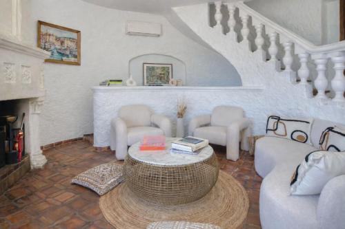 a living room with a table and chairs and a staircase at Villa le repaire in Ramatuelle