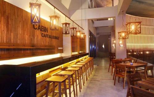 a restaurant with wooden tables and chairs and lights at Cabin Hotel in Jakarta
