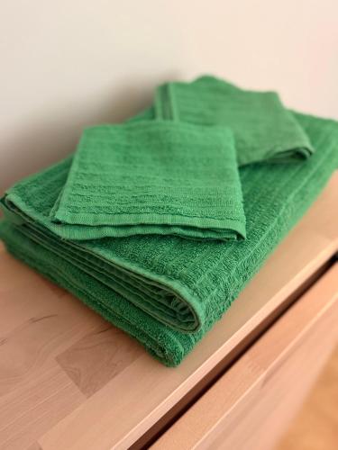 a pile of green towels sitting on top of a wooden table at Apartamenti Ikšķile in Ikšķile