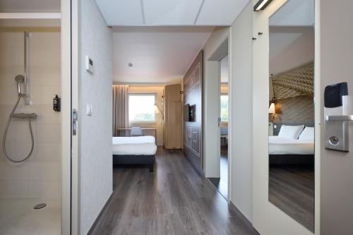 a hotel room with two beds and a bathroom at ibis De Haan in De Haan