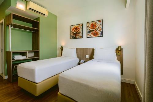 a room with two beds and a shelf at Slim Hotel Cuiabá Aeroporto in Cuiabá