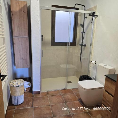 a bathroom with a toilet and a glass shower at Casa Rural El Jaral in Orihuela del Tremedal