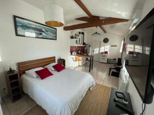 a bedroom with a white bed and a kitchen at L'Opaline-Maisonnette 28m2 grand confort avec jardin-tout inclus in Tully