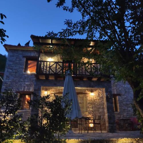 an old stone house with an umbrella in front of it at Kleitor Stone Villa-Peloponnese Getaway in Klitoria