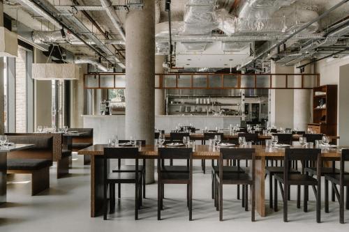 a restaurant with wooden tables and chairs and a kitchen at Mason & Fifth, Westbourne Park in London