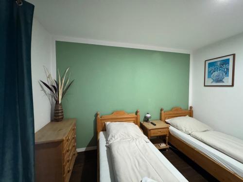 a room with two beds and a green wall at Weissenfelder Guest House & Restaurant in Weißenfeld