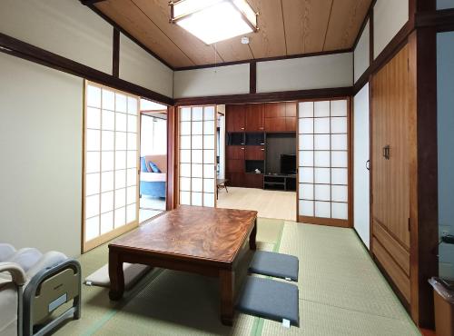 a living room with a wooden table and chairs at させぼ旅の宿KawashimoEn in Sasebo