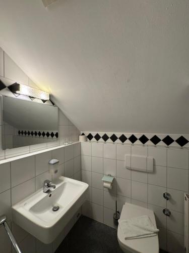 a white bathroom with a sink and a toilet at Weissenfelder Guest House & Restaurant in Weißenfeld