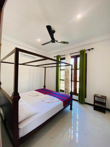 a bedroom with a canopy bed with a fan at Liya Villa in Ahangama