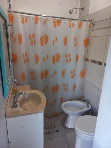 a bathroom with a sink and a toilet and a shower curtain at DPTO con PARQUE, PARRILLA y PISCINA a minutos del centro in Concepción del Uruguay