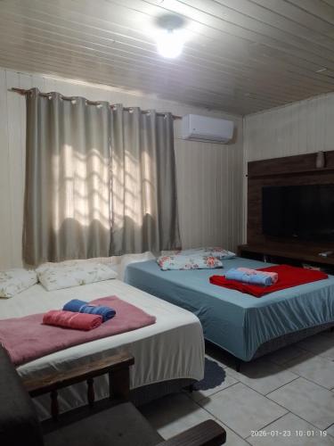 two beds sitting in a room with a tv at Casa de Alquiler Cláudia in Pântano Grande