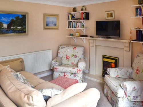 a living room with two chairs and a fireplace at Swallowdale in Flordon