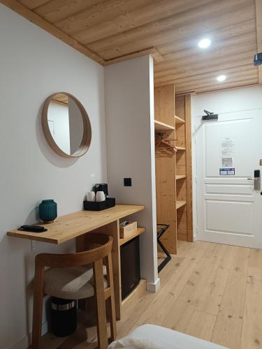 a room with a desk and a mirror and a closet at Hôtel Mont Thabor Serre Chevalier in La Salle-les-Alpes