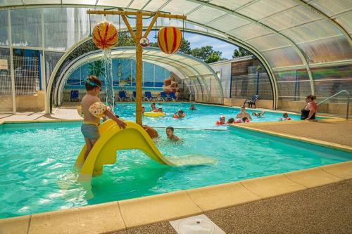 a child playing on a slide in a swimming pool at ZEcamping 4 étoiles animé piscine couverte club enfant mini golf dog friendly in La Faute-sur-Mer
