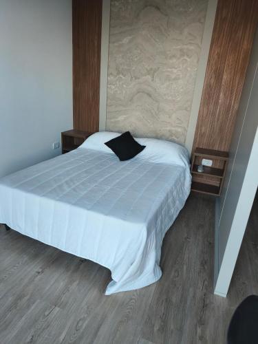 a bedroom with a large bed with white sheets and wood floors at San Pedro, Cristal INN in San Pedro
