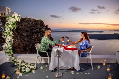 a man and woman sitting at a table with wine glasses at Pegasus Suites & Spa in Imerovigli