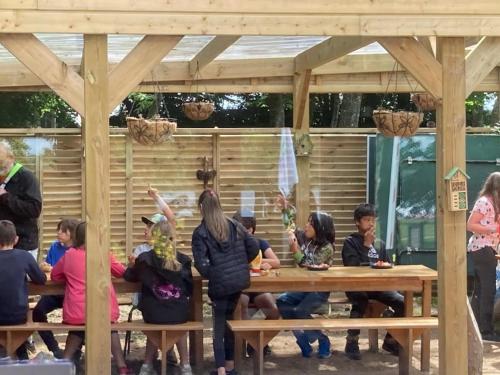a group of children sitting at picnic tables under a pergola at ZEcamping 3 étoiles pet friendly avec sauna bar et restaurant in Priziac
