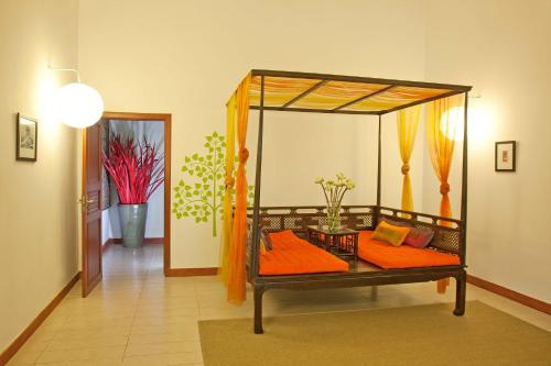 a room with a canopy bed with orange pillows at The Pavilion in Phnom Penh