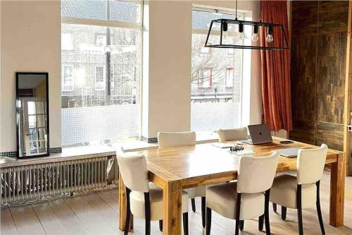 a dining room table with chairs and a laptop on it at Eindhoven City Center Apartment in Eindhoven